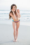 Cheerful slim brown haired model in coloured bikini posing holding her hair