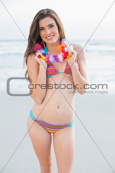 Content slim brown haired model in coloured bikini wearing a flower necklace