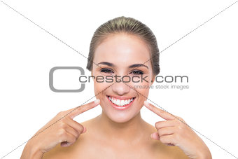Cheerful young woman pointing at her smile