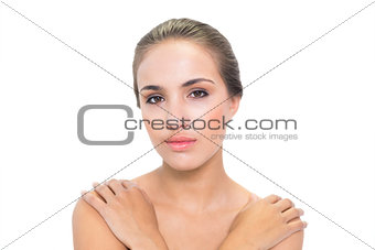 Calm young brunette woman holding her shoulders