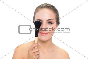 Smiling young brunette woman holding a powder brush