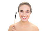 Smiling young brunette woman holding eyebrow brush