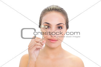 Content young brunette woman using an eyelash curler