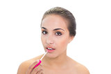 Lovely young brunette woman applying lip gloss