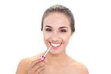 Cheerful brunette woman applying lip gloss
