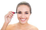 Cheerful young brunette woman applying mascara