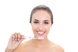 Smiling young brunette woman holding a toothbrush