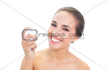 Smiling young brunette woman holding an inhaler