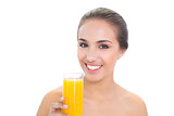 Cheerful brunette woman holding a glass of orange juice
