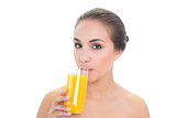 Content brunette woman drinking a glass of orange juice
