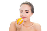 Smiling brunette woman smelling on an orange