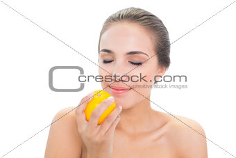Smiling brunette woman smelling on an orange