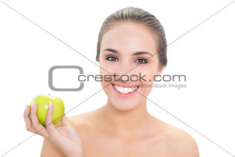 Cheerful young brunette woman holding a green apple