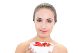 Smiling young brunette woman holding a bowl of strawberries