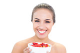 Cheerful young brunette woman holding a bowl of strawberries