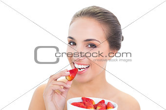 Happy young brunette woman eating a strawberry