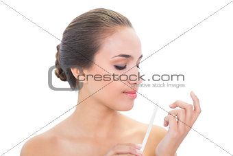 Young brunette woman looking at her nail file