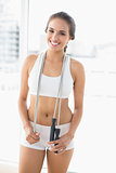 Smiling sporty brunette wearing a skipping rope around the neck