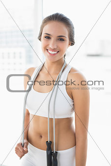 Cheerful sporty brunette wearing a skipping rope around the neck