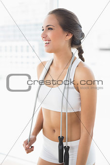 Laughing sporty brunette wearing a skipping rope around the neck