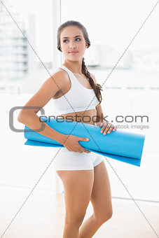 Content sporty brunette woman holding an exercise mat