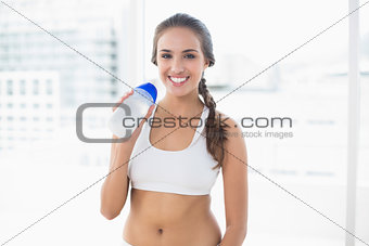 Smiling sporty brunette holding a water bottle