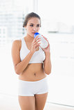 Peaceful sporty brunette drinking from a water bottle