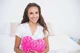 Smiling attractive woman holding heart pillow