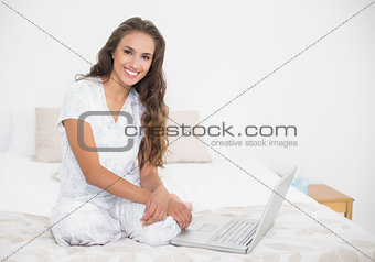 Smiling attractive brunette sitting next to a laptop