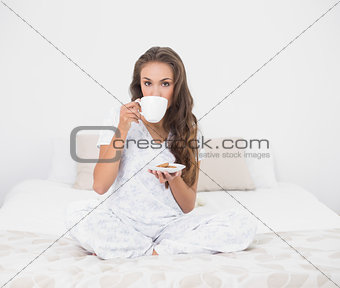 Content attractive brunette drinking from a cup