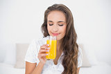 Content attractive brunette holding a glass of orange juice
