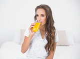 Calm attractive brunette drinking a glass of orange juice