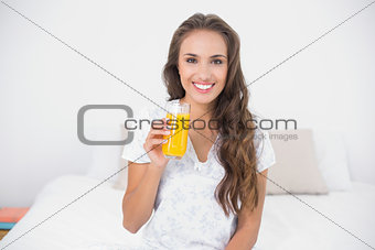 Smiling attractive brunette holding a glass of orange juice
