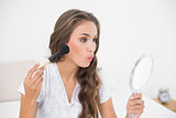 Attractive young brunette holding a brush and a mirror