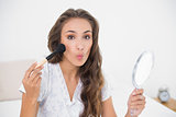 Posing attractive brunette holding a brush and a mirror