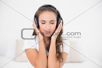 Content attractive brunette listening to music with closed eyes