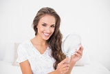 Smiling attractive brunette holding mirror