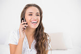 Laughing pretty brunette holding mobile phone