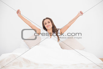 Smiling pretty brunette lying in bed
