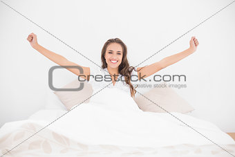 Cheerful pretty brunette lying in bed