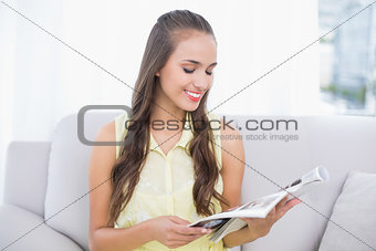 Smiling pretty brunette reading magazine