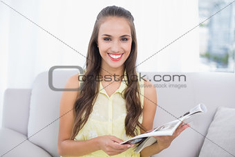 Smiling pretty brunette holding magazine