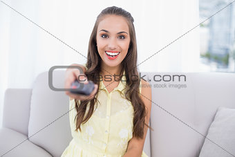 Excited pretty brunette holding remote