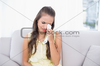 Crying young brunette holding a tissue