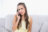 Sad young brunette holding mobile phone