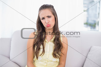 Sad posing brunette sitting on couch