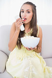 Serious young brunette eating popcorn