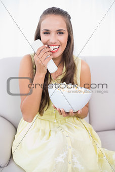 Laughing young brunette eating popcorn