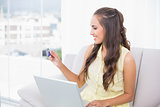 Smiling young brunette looking at credit card