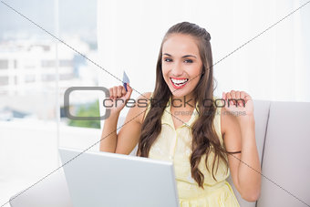 Excited young brunette holding credit card